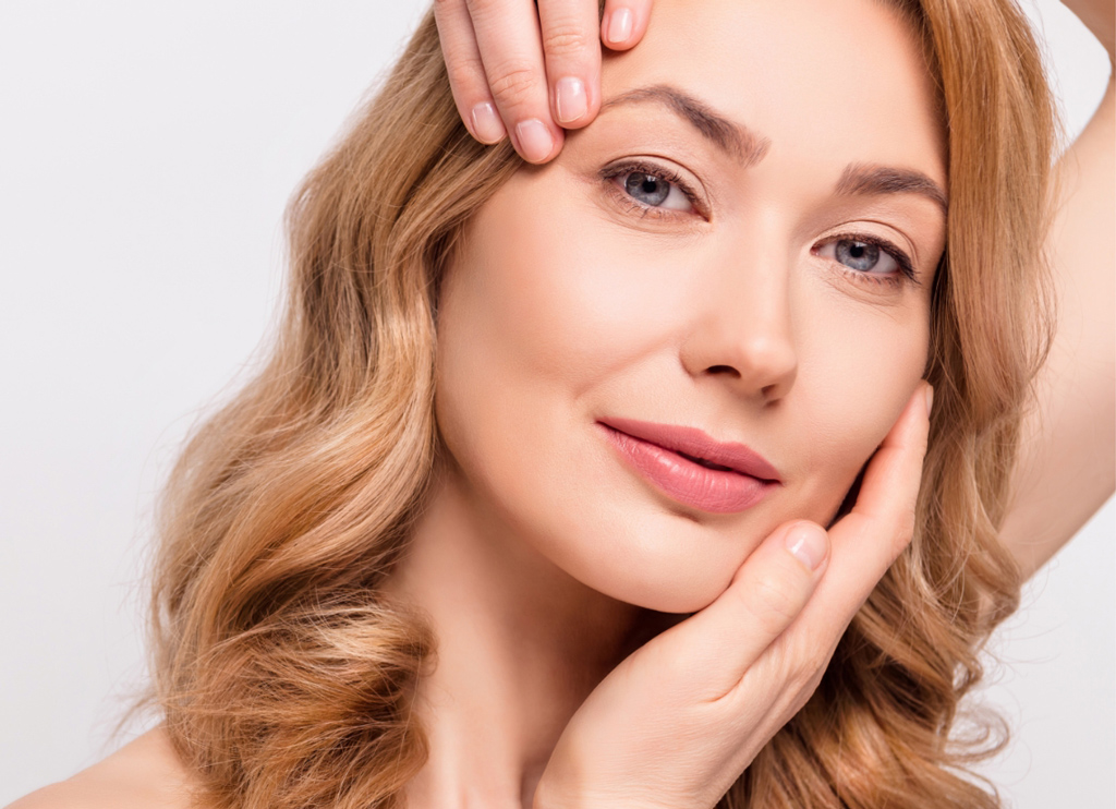 Woman gently lifting facial skin with her hands to highlight a smooth, youthful appearance.